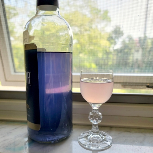 An image of the described drink, next to my bottle of homemade violet liqueur (which is a lovely purple-blue color).